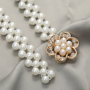 Close-up of elegant white pearl waist chain with a gold floral rhinestone buckle detail