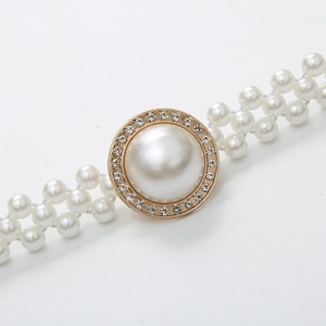 Detailed close-up of a white faux pearl belt with a golden rhinestone circular buckle