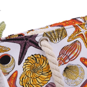 Close-up of nautical canvas tote bag featuring shell prints and beige rope handle details