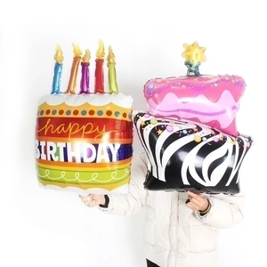Large rainbow birthday cake foil balloon with candles held by a person for party decoration