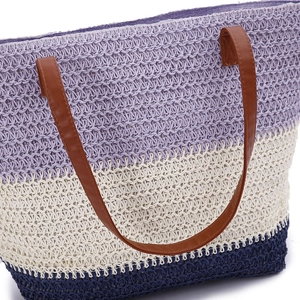 Detail of woven beach tote showing purple and blue stripes with brown leather handles