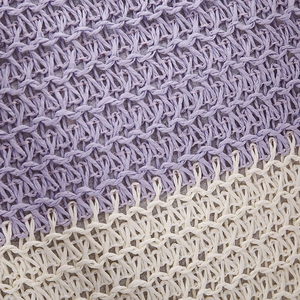 Detailed macro view of woven straw shoulder bag in purple and beige texture