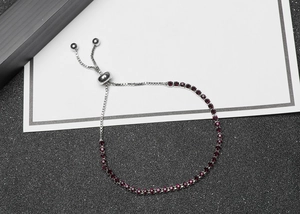 Detail of adjustable slider bracelet with dark red zircons in silver finish chain