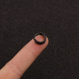 Close-up of black triple braided helix earring on finger showing textured surface