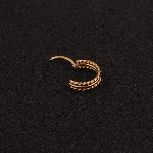 Macro detail of golden double-layered twisted rope hoop earring with hinged closure