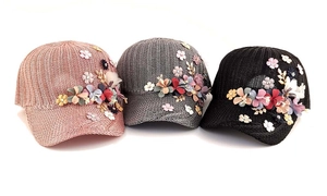 Detailed view of three knitted baseball caps in pink, grey and black with 3D floral accents