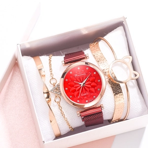 Close-up of women's gold watch with red floral dial and matching cat-ear bracelets in box