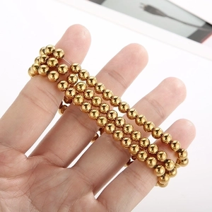Elegant multi-layer golden bead bracelet set with polished metallic finish on model's hand