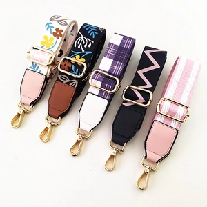 Close-up of five adjustable ethnic style wide bag straps with gold metal hooks