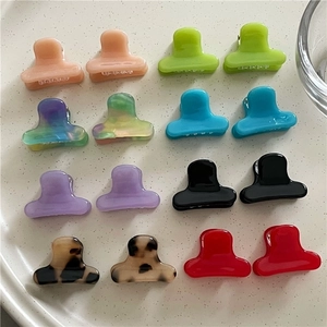 Colorful mini acetate hair claws for women in a white ceramic dish, assorted bright colors