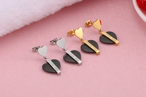 Gros plan de boucles d'oreilles cœur en or et argent avec gravure I Love You sur rose
