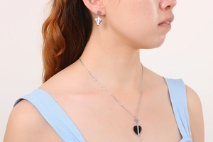 Gros plan d'un mannequin portant un ensemble collier et boucles d'oreilles cœur noir