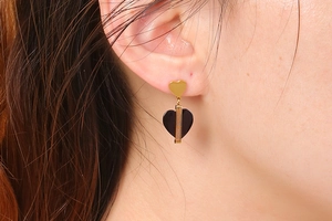 Détail de boucles d'oreilles cœur doré gravées I Love You portées par un mannequin