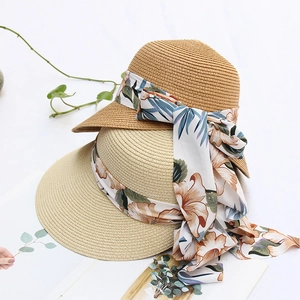 Close-up of straw sun hats featuring elegant floral ribbon bows in camel and beige colors