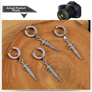 Detailed macro view of four silver sword-shaped punk earrings on a rustic wood slice