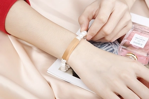 Detailed view of pearl bracelet with golden metal bar on elegant silk background