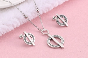 Silver jewelry set with hollow circle design and clear crystals on pink plush fabric