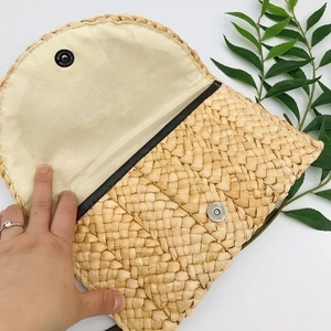 Handmade woven corn husk clutch bag with magnetic closure and beige fabric lining