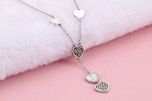 Silver heart necklace with diamonds and shell inlays on pink background