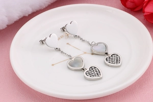 Detail of silver drop earrings featuring heart-shaped shell and sparkling zircon accents