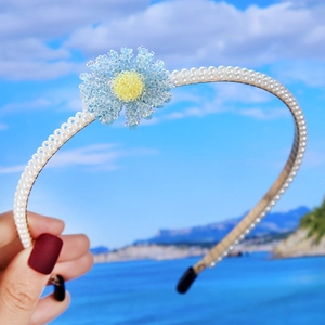 Detailed view of light blue beaded flowers and white pearls on a bridal headband