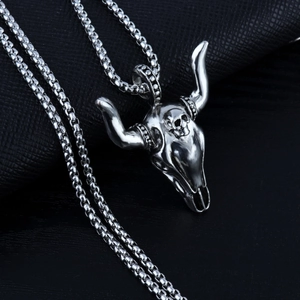 Close-up of a silver bull skull pendant necklace on black leather background