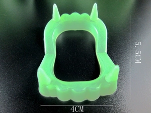Detailed view of green glowing vampire teeth toy showing dimensions 5.5cm by 4cm