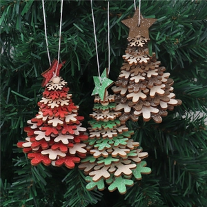 Detailed view of layered wooden snowflake Christmas ornaments with bells on green branches