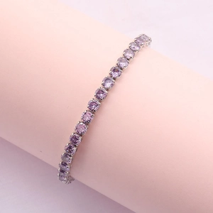 Macro detail of silver tennis bracelet with purple round-cut zircon stones on a pink stand