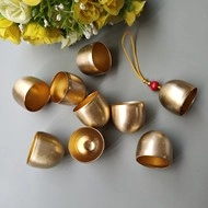 Detailed shot of golden bells with a red bead and cord accessory on a neutral background