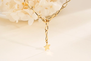 Makroaufnahme des goldenen Sternanhängers und Karabinerverschlusses an der Halskette