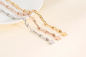 Detailansicht von drei metallischen S-Link-Ketten mit Sternanhängern in Gold, Silber und Roségold