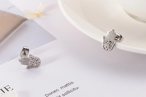 Detailed view of silver Hamsa hand stud earrings featuring intricate cutout design