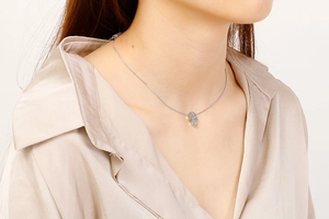 Silver palm-shaped pendant necklace displayed on a model neck with fine chain detail