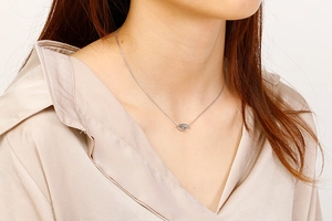 Close-up of minimalist silver twisted pendant necklace worn by a model in a studio