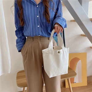 Close-up of minimalist white canvas lunch bag with snap button closure and handle
