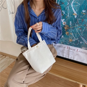 Detailed view of white canvas lunch bag with vintage bronze button in a lifestyle setting