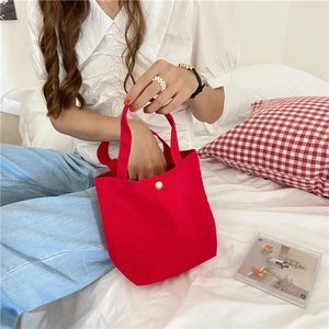 Detail view of red canvas bento bag with metal snap button and dual handles