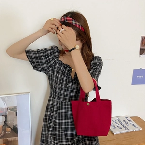 Detail of red canvas tote bag with metal magnetic closure and durable texture
