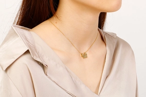 Dettaglio ravvicinato di una collana dorata con ciondolo a figure su una modella