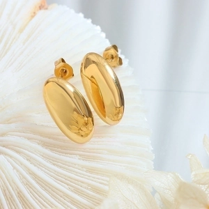 Polished 18K gold plated oval rice-shaped stud earrings on white coral display