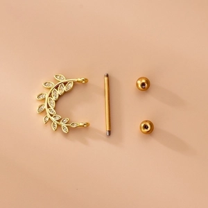 Golden stainless steel leaf nipple ring set with zircon inlay on a beige background