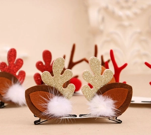 Détail de pinces à cheveux bois de renne de Noël avec paillettes dorées et pompon blanc