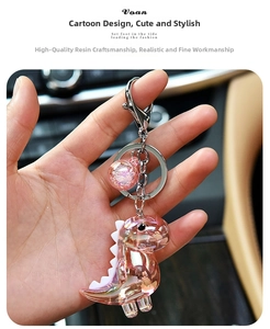 Iridescent pink acrylic cartoon dinosaur keychain with glitter ball charm in macro detail