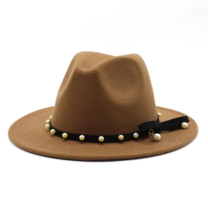 Macro shot of camel wool fedora hat with black band and white pearl tassel detail