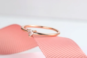 Macro di anello a cuore in oro rosa con zircone su nastro di raso rosa