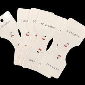 Fan-shaped stack of pink paper display cards with red cherry patterns for accessories