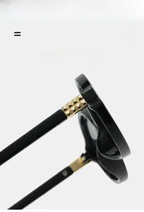 Detailed close-up of glossy black frame hinge with gold pyramid stud and metal hardware