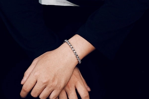 Macro detail of silver stainless steel square box chain bracelet on a model wrist