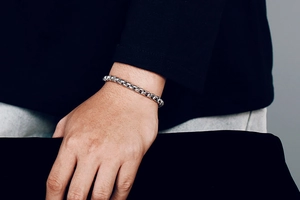 Close-up of a minimalist silver stainless steel chain link bracelet worn on a wrist